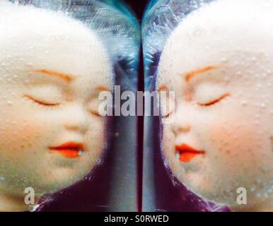 A mirror image of doll faces. Stock Photo