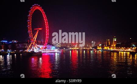 London Eye illuminated and River Thames view and reflections at night on the Embankment in Westminster in the West End of London, UK, a panoramic view of some of the iconic tourist attractions Stock Photo