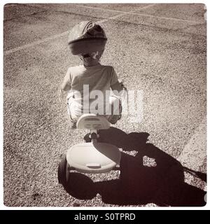 Little girl riding a tricycle in an empty parking lot Stock Photo