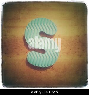 Textured foam letter S on a grungy wood background Stock Photo