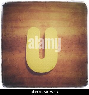 Textured foam letter U on a grungy wood background Stock Photo