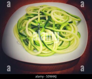 Freshly spiralized  raw zucchini strands on a white plate. Stock Photo