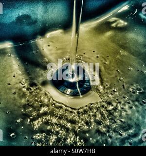 Water running down the drain in bathroom sink Stock Photo