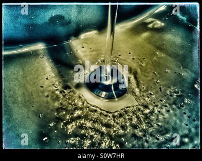 Water running down the drain in bathroom sink Stock Photo