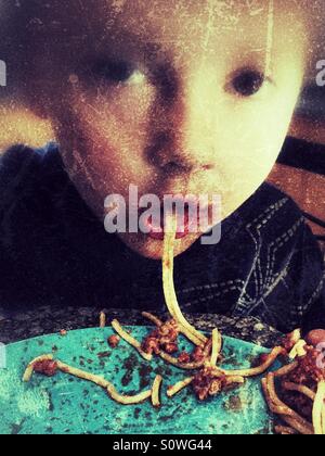 Boy sucking up a piece of spaghetti Stock Photo