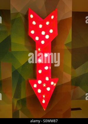 Brightly lit red arrow points down Stock Photo