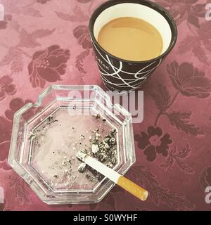 Coffee and cigarette in ashtray on table top view Stock Photo