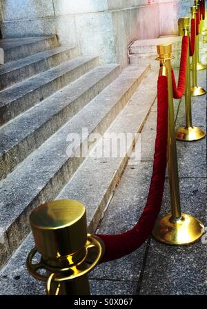 Red velvet ropes and brass stanchions keep an event exclusive. Stock Photo