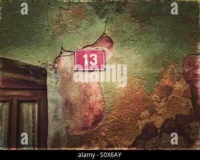 House number 13 on a peeling colorful facade Stock Photo