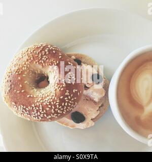 Smoked salmon cream cheese, capers in sesame bagel and a cup of latte. Stock Photo