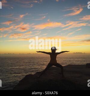 Woman doing yoga on the cliff Stock Photo