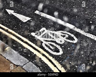 Bicycle sign and directions on a road . Seen through s wet window with raindrops from above. Stock Photo