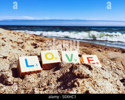 Child's blocks spelling out the word 'love' on a sandy beach Stock Photo