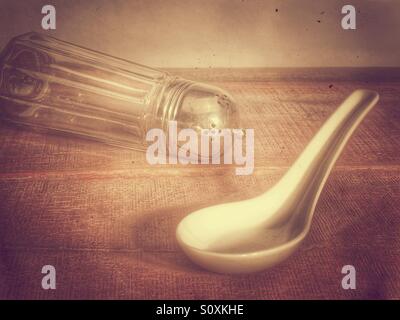 Old fashioned sugar shaker resting on a old fashioned wooden worktop Stock Photo