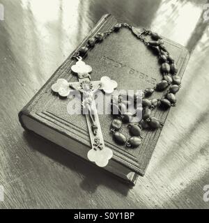 Rosary beads and crucifix resting on holy bible. Stock Photo