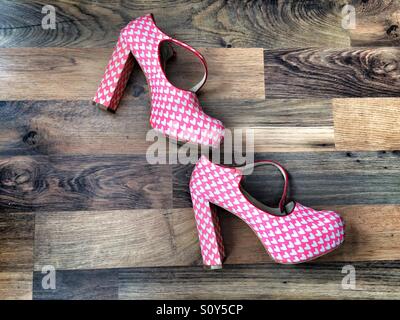 A pair of ladies heeled shoes with a repeat pattern of hearts, on a wooden floor Stock Photo