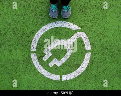 Standing next to electric car recharging point sign Stock Photo