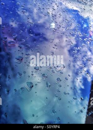 Water drops and the reflection of the sky on a car windscreen. Stock Photo
