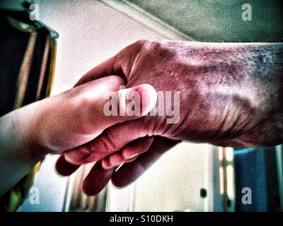 An adult male hand holding a young child's hand. Stock Photo
