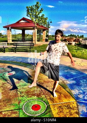 Teenage Boy with Autism and Down's Syndrome playing at the water park in the summer Stock Photo