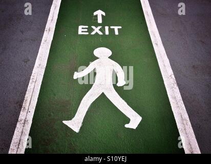 An exit sign showing a walking man painted on the concrete floor of a multi-storey car park Stock Photo