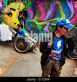 A Colombian street vendor stands in front of a graffiti artwork, created by an artist named Stinkfish, in the center of Bogotá, Colombia, 21 February, 2016. Stock Photo