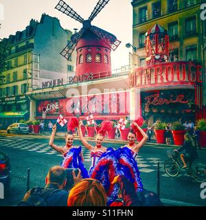 Three female dancers posing in front of the Moulin Rouge cabaret in Paris, France Stock Photo