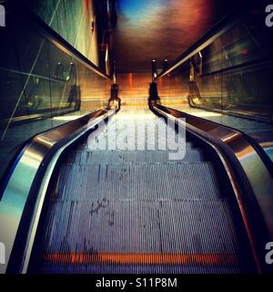 Escalators or moving staircase goinf down in a mall or building with a mechanic machine machinery for people going down Stock Photo