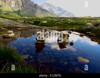 Cairns in to the water And sky reflection. San Bernardino Pass, Switzerland Stock Photo