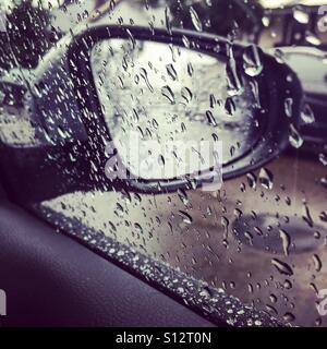 Rain falling on a car window and side view mirror Stock Photo