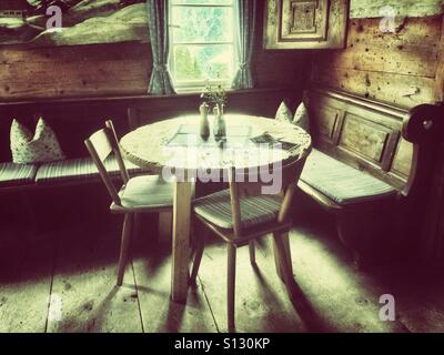 A round corner table with two chairs and a bench in the Stutzalpe (Stutz Alpe) on the slope of the Austrian mountain Walmendingerhorn, Mittelberg, Kleinwalsertal, Alps, Austria Stock Photo