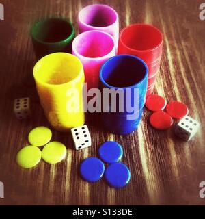 Dices, pieces and cups on a wooden table Stock Photo