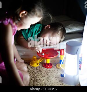 Toddler and your girl play with a marble run toy at bedtime by lamp light Stock Photo