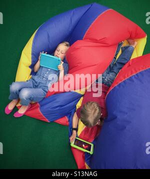 An aerial view of a pair of siblings playing on their tablets. Stock Photo