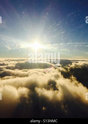Looking out an airplane window at clouds and the sun. Stock Photo