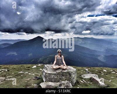 Girl sitting in lotus position in front of the mountains Stock Photo