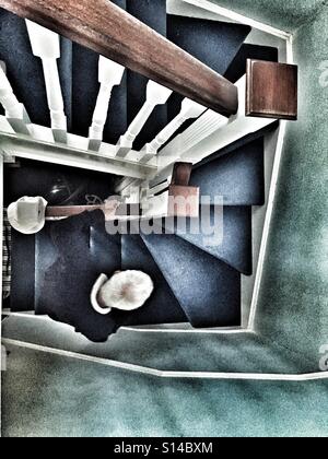 Elderly man walking upstairs cautiously, hand on bannister Stock Photo