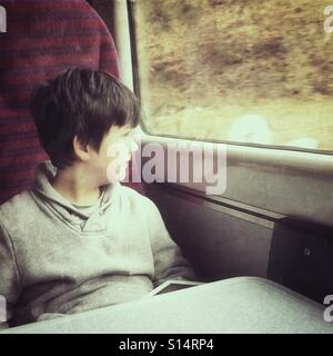 Boy on train looking out window Stock Photo