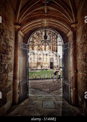 Couple walking past the Radcliffe Camera, seen through a passageway leading from the Bodleian Library, university of Oxford, England Stock Photo