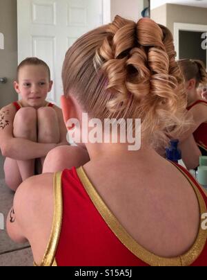 Girl Sits On Bathroom Counter Brushing Hair And Sister Brushes
