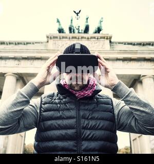 Man wearing VR virtual reality headset at Brandenburg gate in Berlin Stock Photo