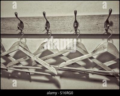 A toned monochrome image of wooden coat hangers lined up and waiting to be used. Where are all the coats, shirt or other items of clothing? Photo Credit © COLIN HOSKINS. Stock Photo