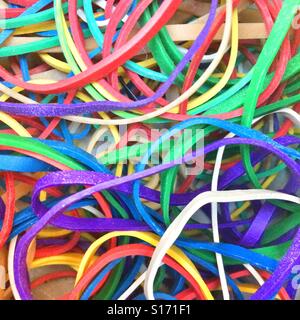 Colorful assortment of rubber bands spread out on a wooden surface showcasing vibrant hues and varied sizes Stock Photo