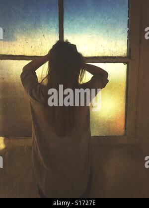 Rear view of a stressed woman head in hands by the window Stock Photo