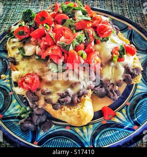A Mexican mollete, a comforting and delicious  open-faced sandwich, is made with a crusty bolillo bread base and is topped with beans, melted cheese, and fresh pick de gallo salsa. Stock Photo