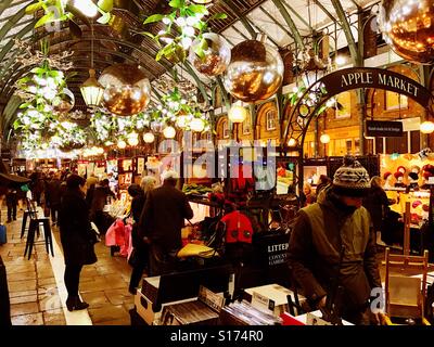 The Apple Market in Covent Garden, London at night, busy with people shopping. Stock Photo