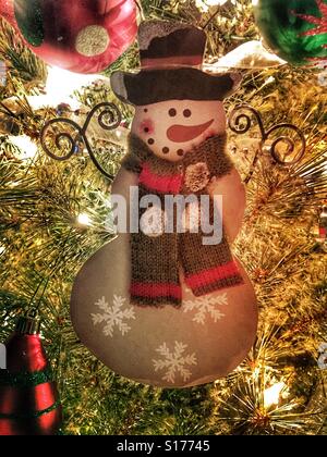 A wooden snowman ornament hanging on a Christmas tree. Stock Photo