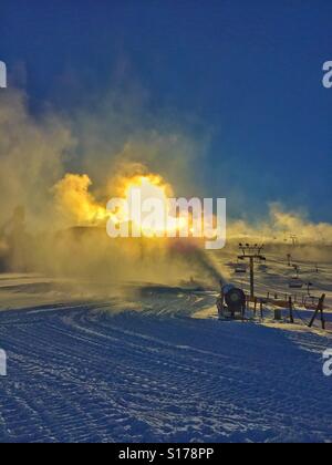 Preparing the ski hill - snow making and bright sun in the background Stock Photo