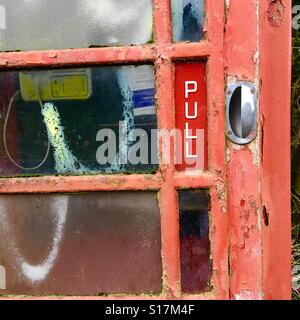 Door on an old red BT public telephone box in need of repainting Stock Photo