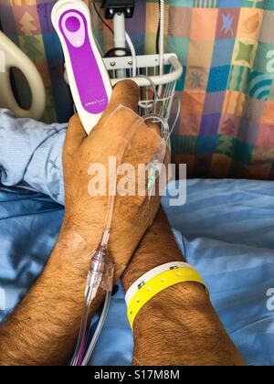 Hospital bed with a patient holding a morphine pump in his hand. Post-surgical pain management with a hand-held device. Alternative to epidural. Time limited to prevent OD. Modern Stock Photo
